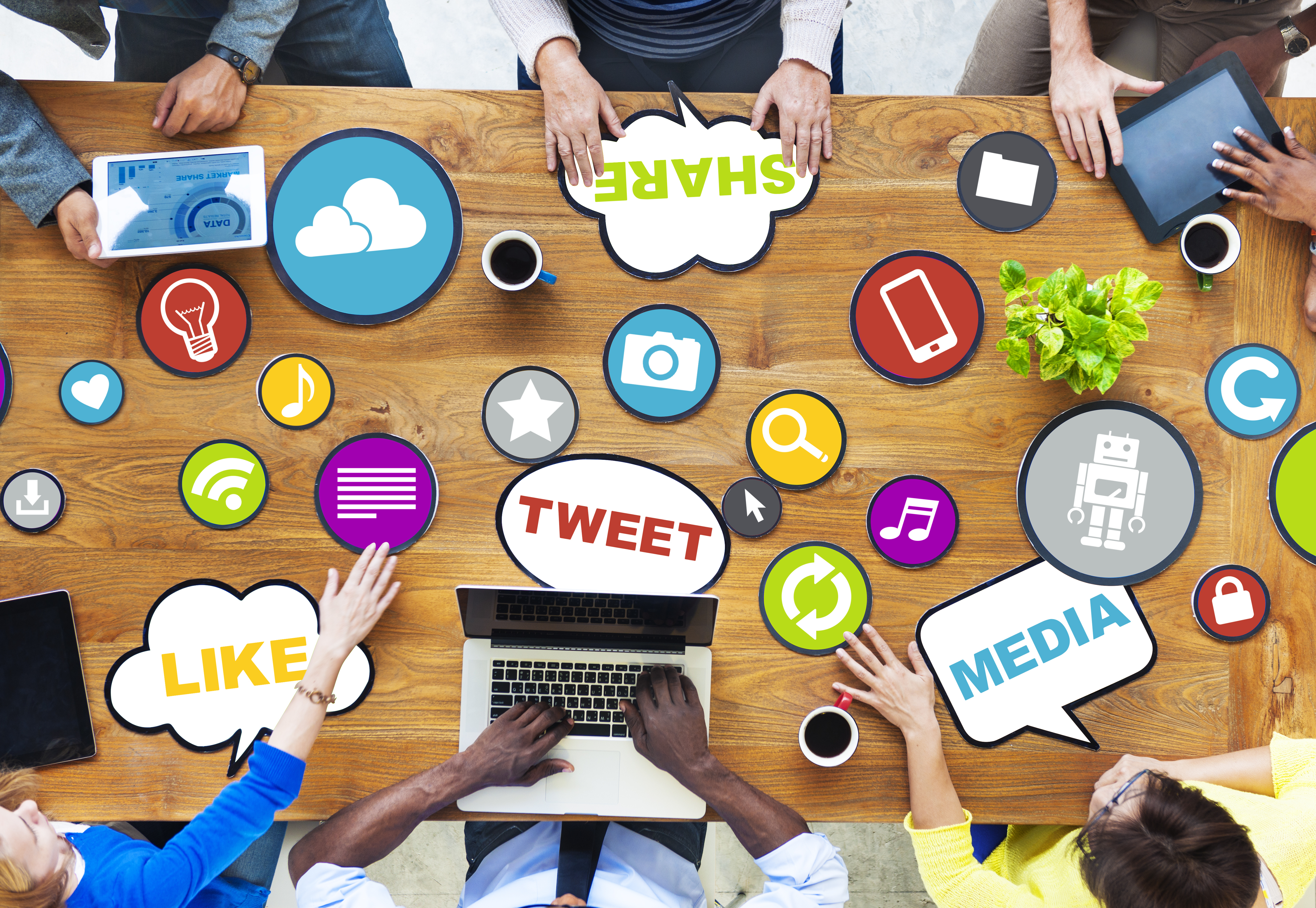 Six people at a table with a bunch of web icons scattered around a table